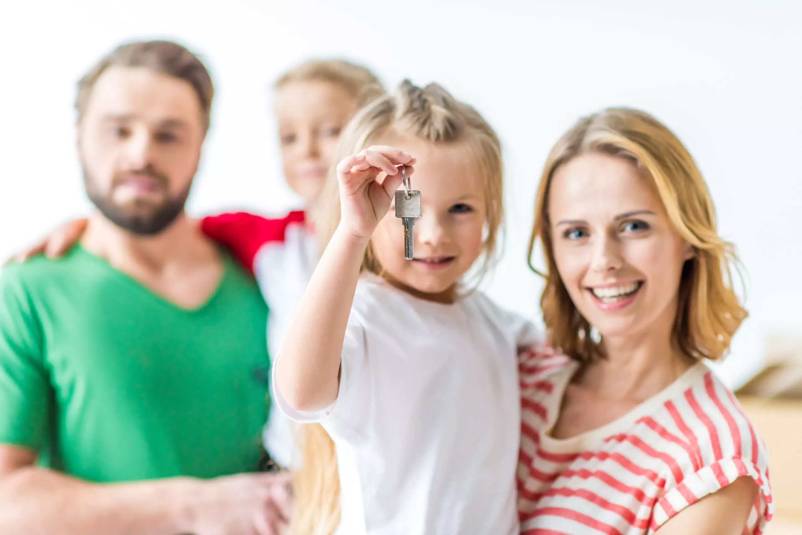 Little girl holding key from new house ready to move with her family into new house isolated on white